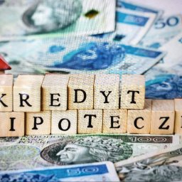 Agnieszka Adamczyk Ekspert ds. Kredytów Hipotecznych - Drewniane klocki z napisem 'KREDYT HIPOTECZNY' na tle banknotów polskich złotych i miniatury domu z czerwonym dachem.