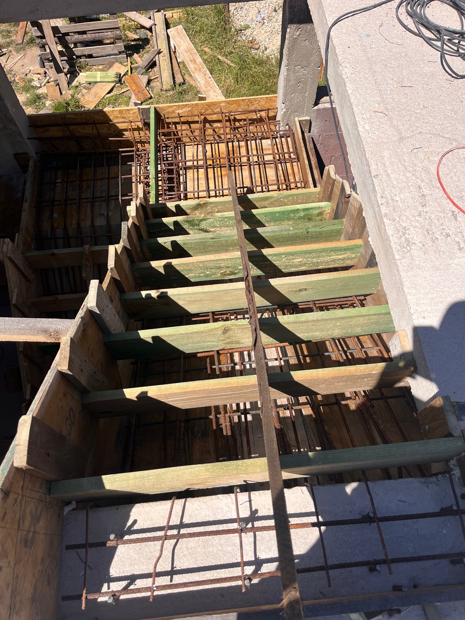 Szczegóły szalunku i zbrojenia schodów betonowych w Rosanowie. Drewniane deski i stalowe pręty tworzą konstrukcję przed wylaniem betonu.