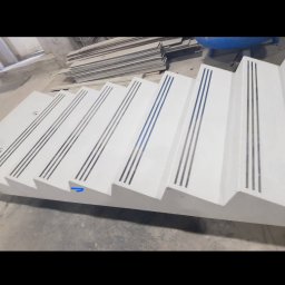 olimp-bud paweł czaja - Prefabrykowane betonowe schody z antypoślizgowymi wstawkami, widoczne w warsztacie, czekające na montaż.