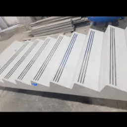 Prefabrykowane betonowe schody z antypoślizgowymi wstawkami, widoczne w warsztacie, czekające na montaż.