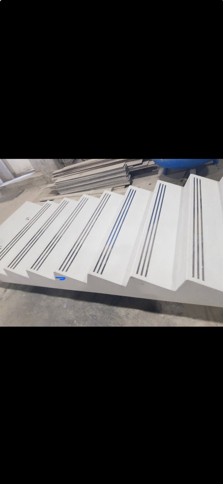 Prefabrykowane betonowe schody z antypoślizgowymi wstawkami, widoczne w warsztacie, czekające na montaż.