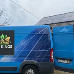 Niebieski samochód dostawczy z logo Eko Kings i grafiką paneli słonecznych na tle domu z panelami fotowoltaicznymi na dachu i rozstawioną drabiną.