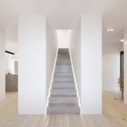 FILIP RAUPUK ARCHITEKTURA - Minimalistyczne wnętrze z marmurowymi schodami podświetlonymi LED. W tle widoczna kuchnia i dekoracyjne trawy w wazonie. Jasna podłoga z drewna. Stonowana kolorystyka.