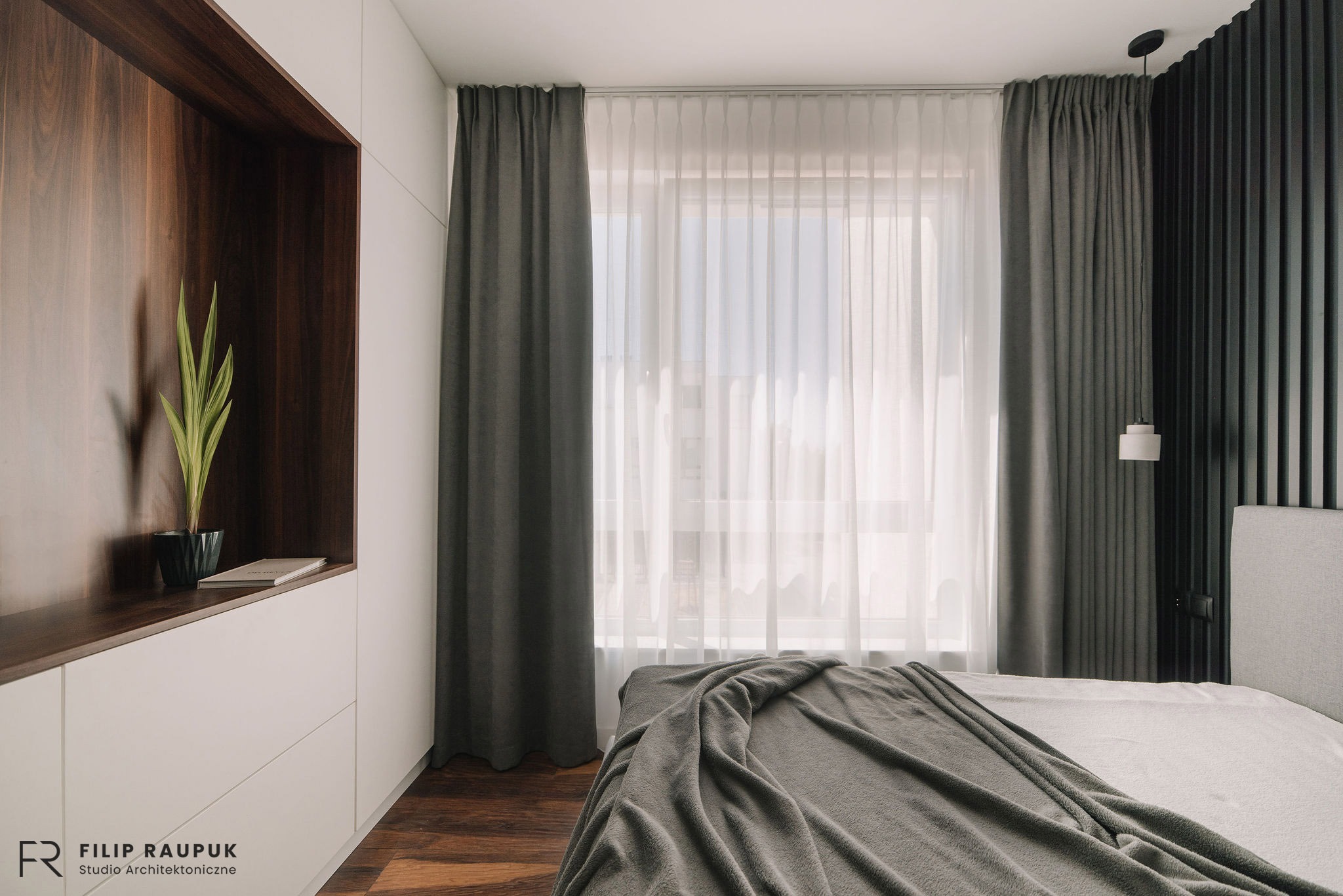 Nowoczesna sypialnia z drewnianą zabudową, zasłonami w odcieniach szarości i dekoracyjną ścianą z lameli. Na podłodze drewniany parkiet.