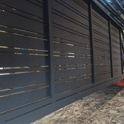 WOKA STAL WOJCIECH KALIKA - Ciemnoszara metalowa brama przesuwna z poziomymi szczelinami, wykończona farbą proszkową z efektem brokatu, widoczna z perspektywy pod kątem na tle wzorzystej podłogi.