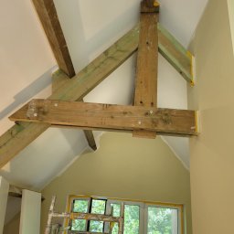 Dominika Kazuch - Drewniana konstrukcja stropu w trakcie prac w Świętochłowicach, zabezpieczona taśmą malarską, widoczny fragment rusztowania i okno.