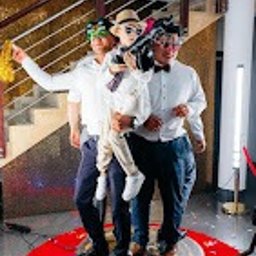 Twoje360chwil - Trzy osoby, w tym dziecko, pozują na obrotowej platformie z rekwizytami na tle schodów z metalową balustradą, prawdopodobnie podczas imprezy.