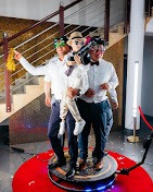 Trzy osoby, w tym dziecko, pozują na obrotowej platformie 360 stopni z rekwizytami imprezowymi w Rzeszowie. W tle schody z metalową balustradą i złota ściana.