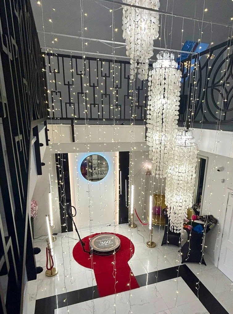 Widok z góry na przygotowaną strefę z obrotową platformą 360° na czerwonym dywanie, oświetloną lampami LED i girlandami świetlnymi, dekorowaną wiszącymi żyrandolami z muszelek.