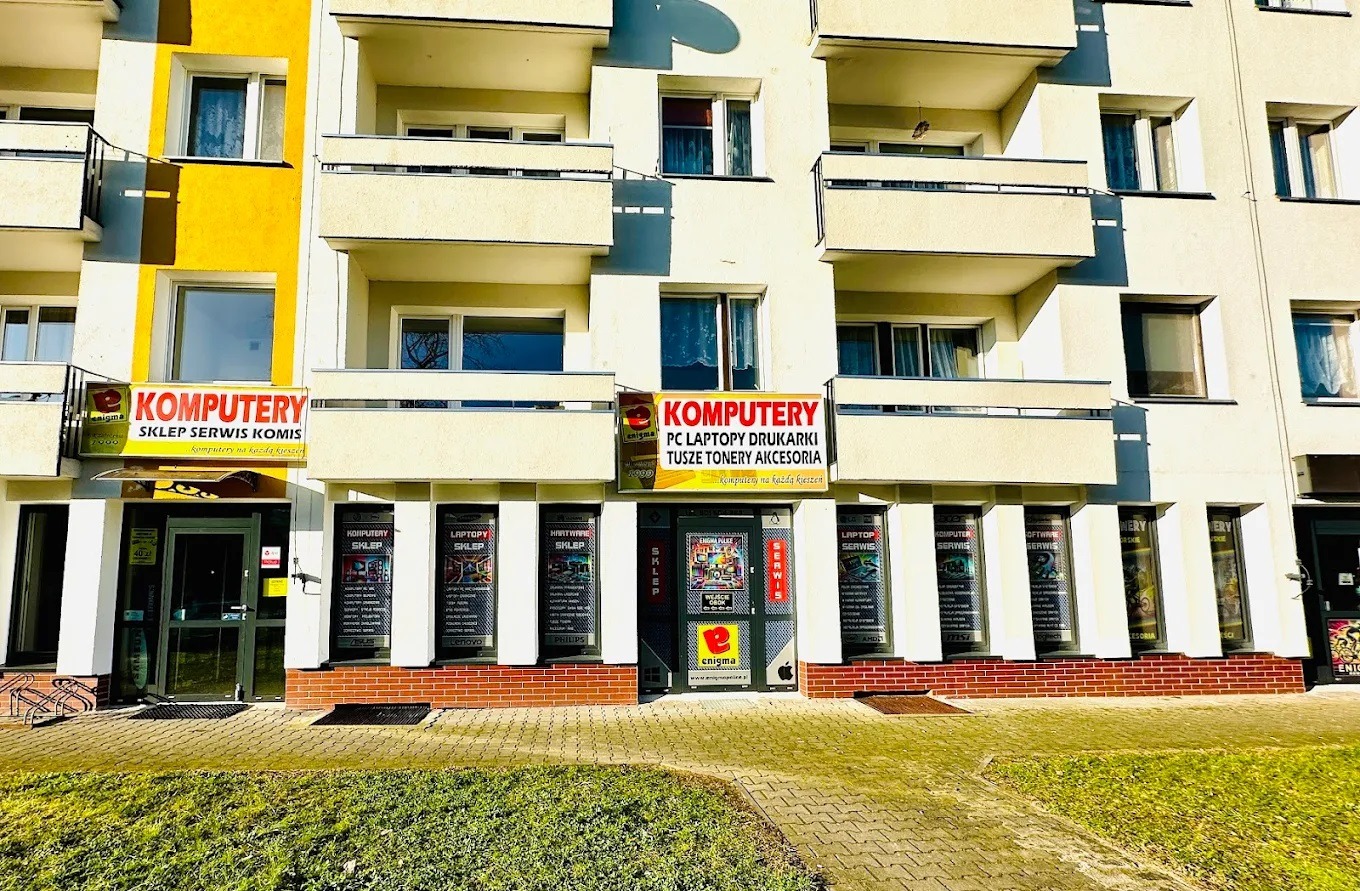 Fasada budynku w Policach z widocznymi dwoma lokalami usługowymi o nazwie 'Komputery', oferującymi serwis, sprzedaż i komis komputerów, laptopów, drukarek, tuszy i tonerów.