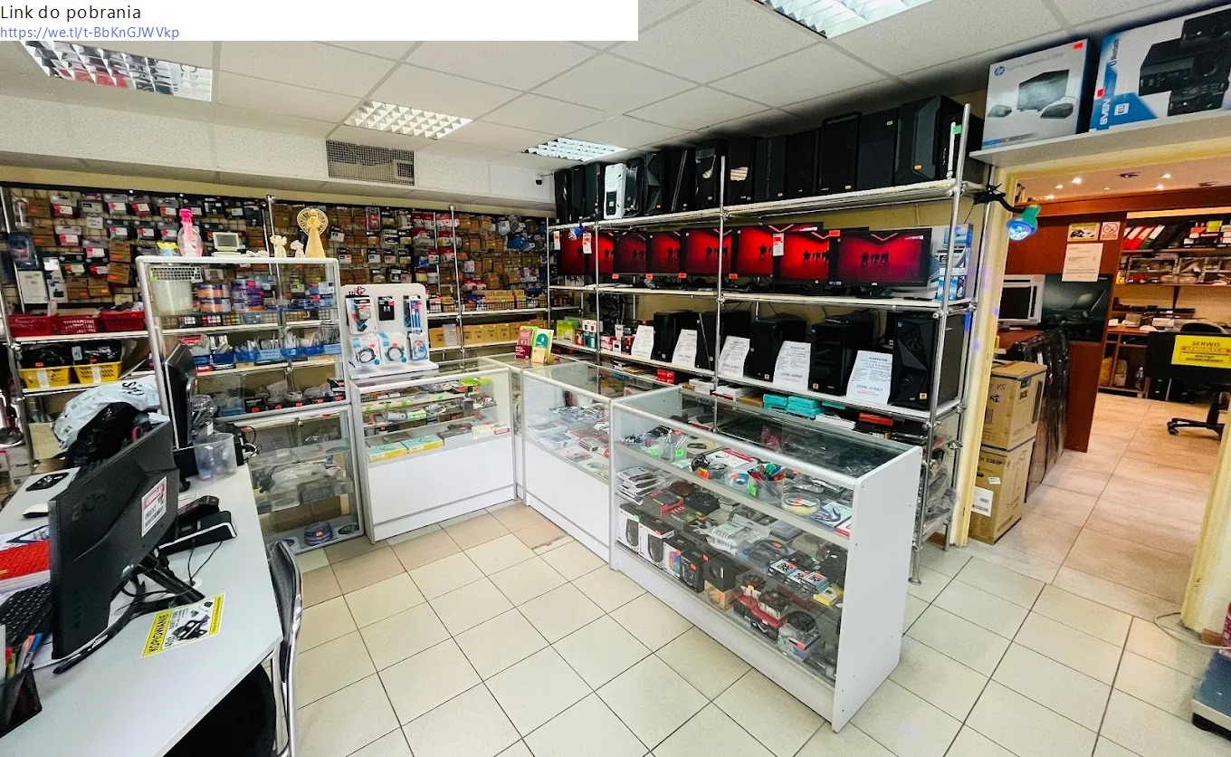 Wnętrze sklepu z elektroniką i komputerami, widoczne regały z komputerami, monitorami, komponentami i akcesoriami, oświetlenie sufitowe z rastrami.