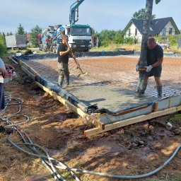 MSS MAREK WIĄCEK - Wylewka fundamentu domu jednorodzinnego z użyciem pompy do betonu. Widoczne zbrojenie, szalunek i pracownicy podczas rozprowadzania betonu.