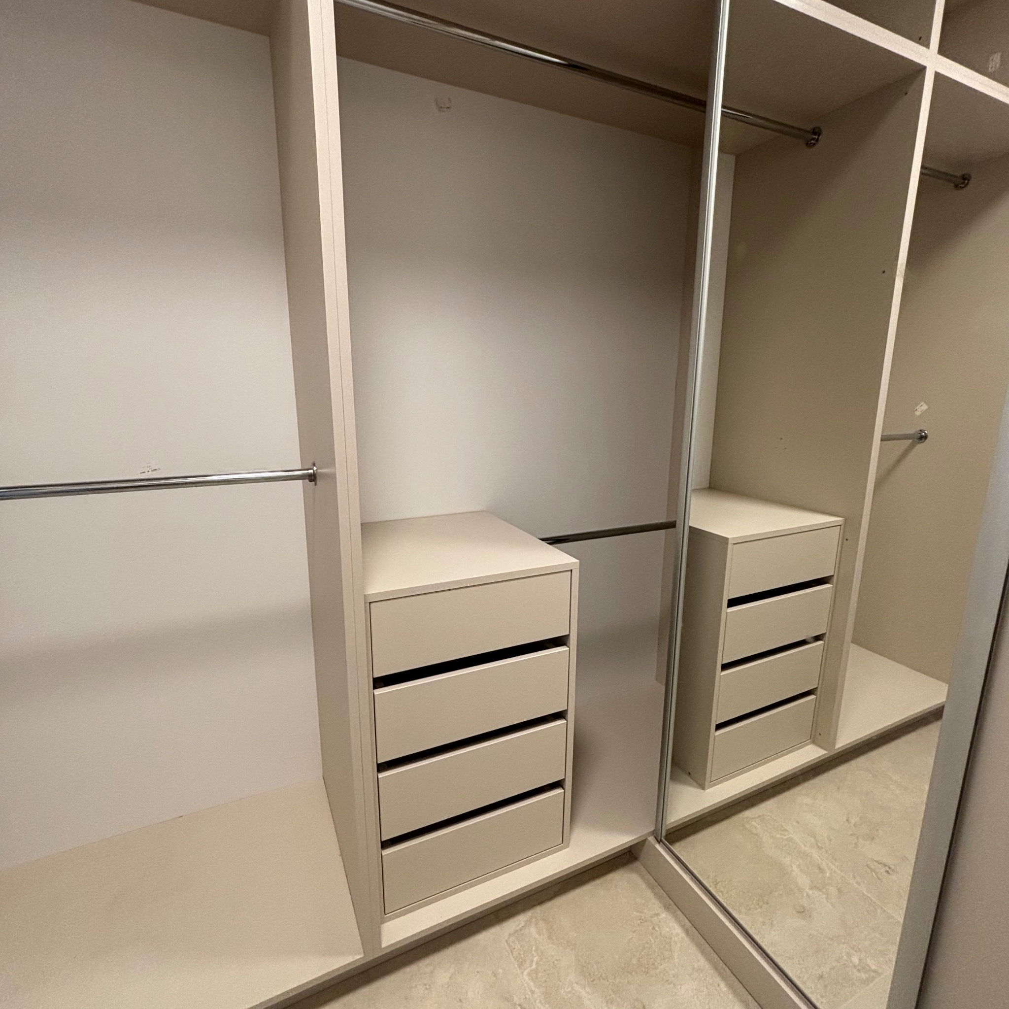 Jasna szafa wnękowa z przesuwnymi drzwiami lustrzanymi i czterema szufladami, widok z bliska, minimalistyczny design.