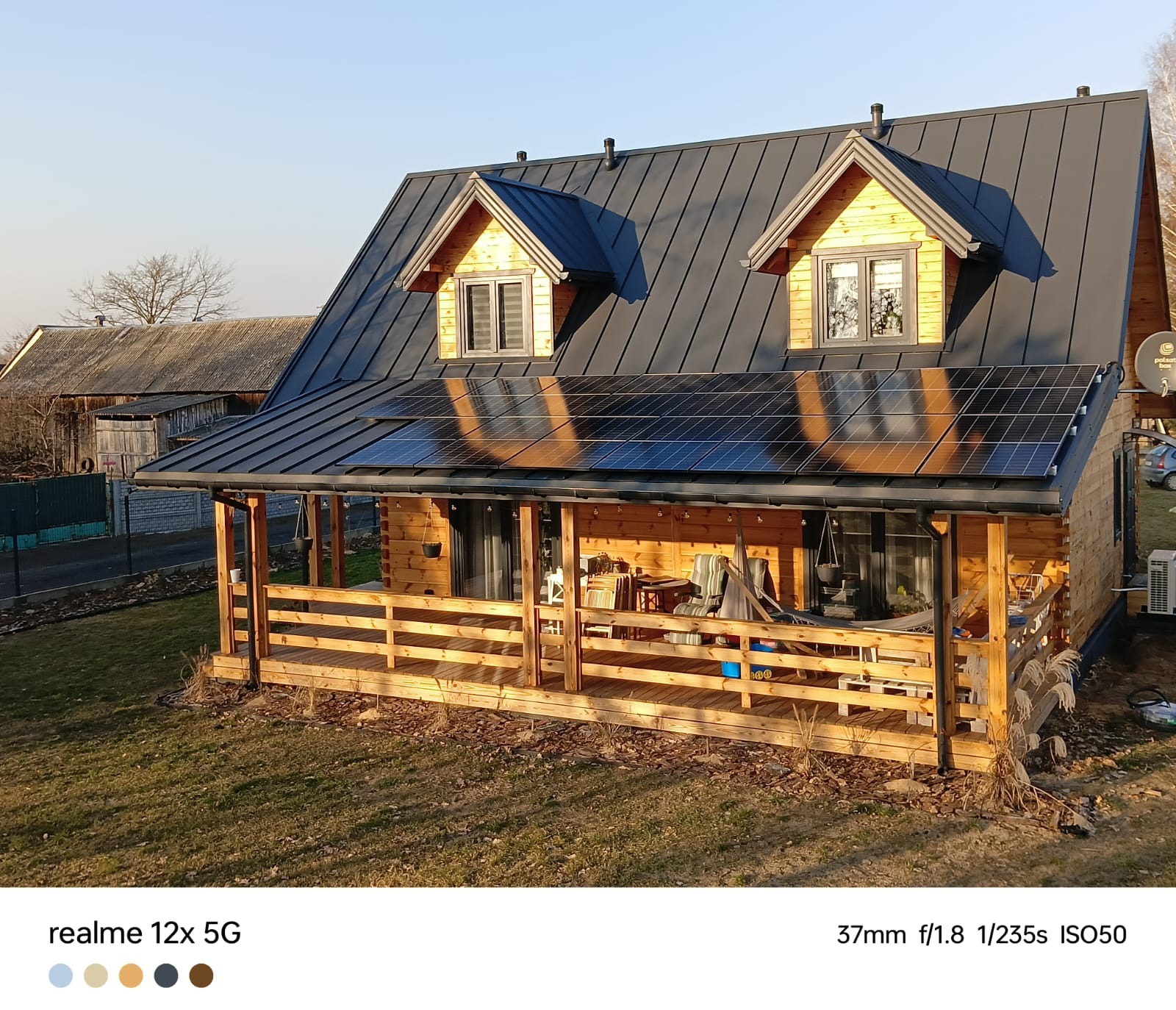 Drewniany dom z panelami słonecznymi na dachu w Radomiu, widok z góry na budynek z tarasem.