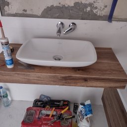 Michał Gwizdek - Montaż umywalki nablatowej Villeroy&Boch z drewnianym blatem, widoczne narzędzia i materiały budowlane w trakcie prac wykończeniowych łazienki.