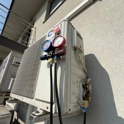 Aleksy Witkowski Kondmaster - Podłączenie manometrów do klimatyzatora zewnętrznego na elewacji budynku. Widoczne przewody i zawory. Diagnostyka klimatyzacji w trakcie serwisu.