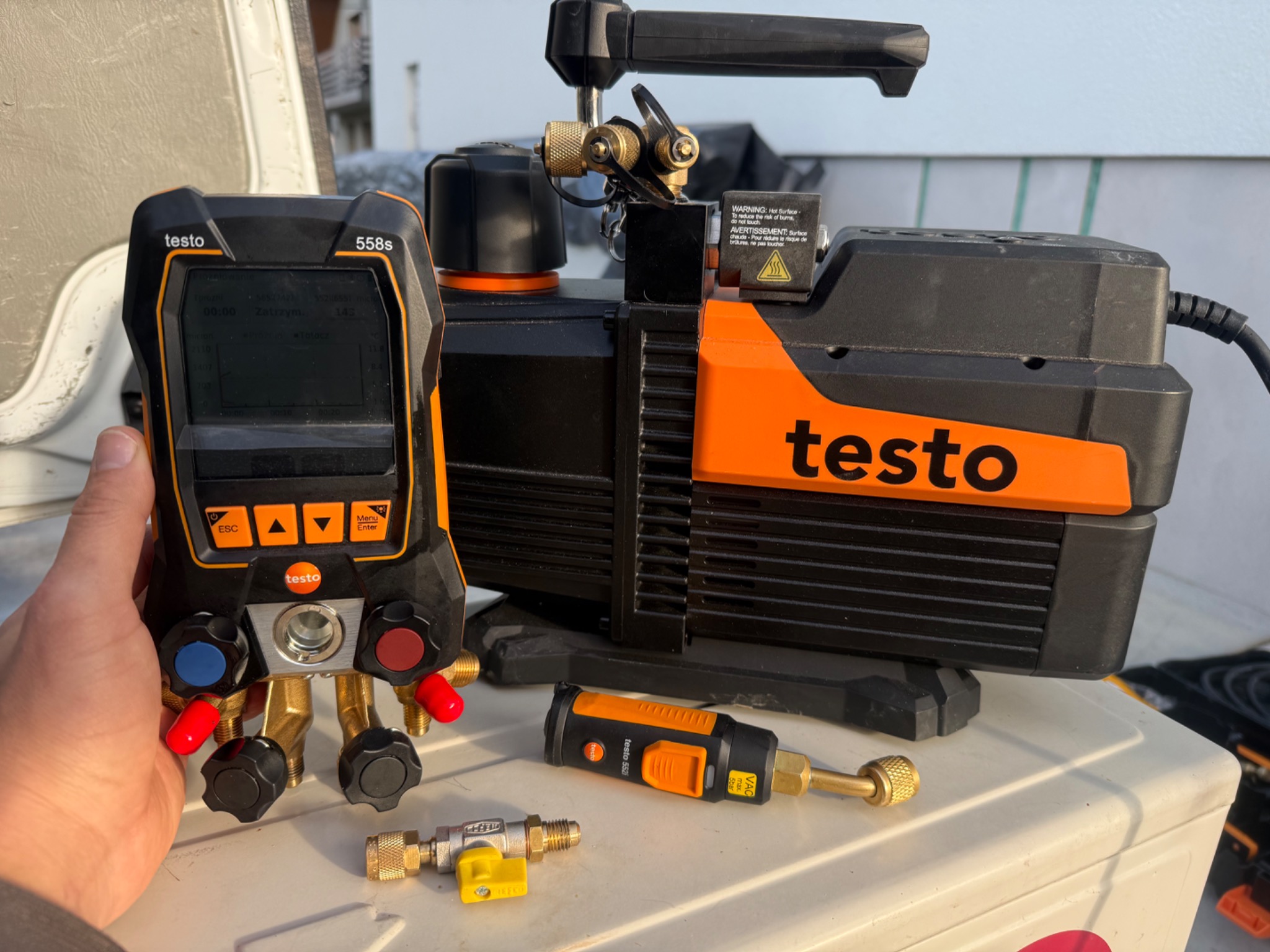 Profesjonalny zestaw narzędzi marki Testo do serwisu klimatyzacji, w tym manometr cyfrowy 558s i pompa próżniowa, gotowy do użycia podczas naprawy lub konserwacji.