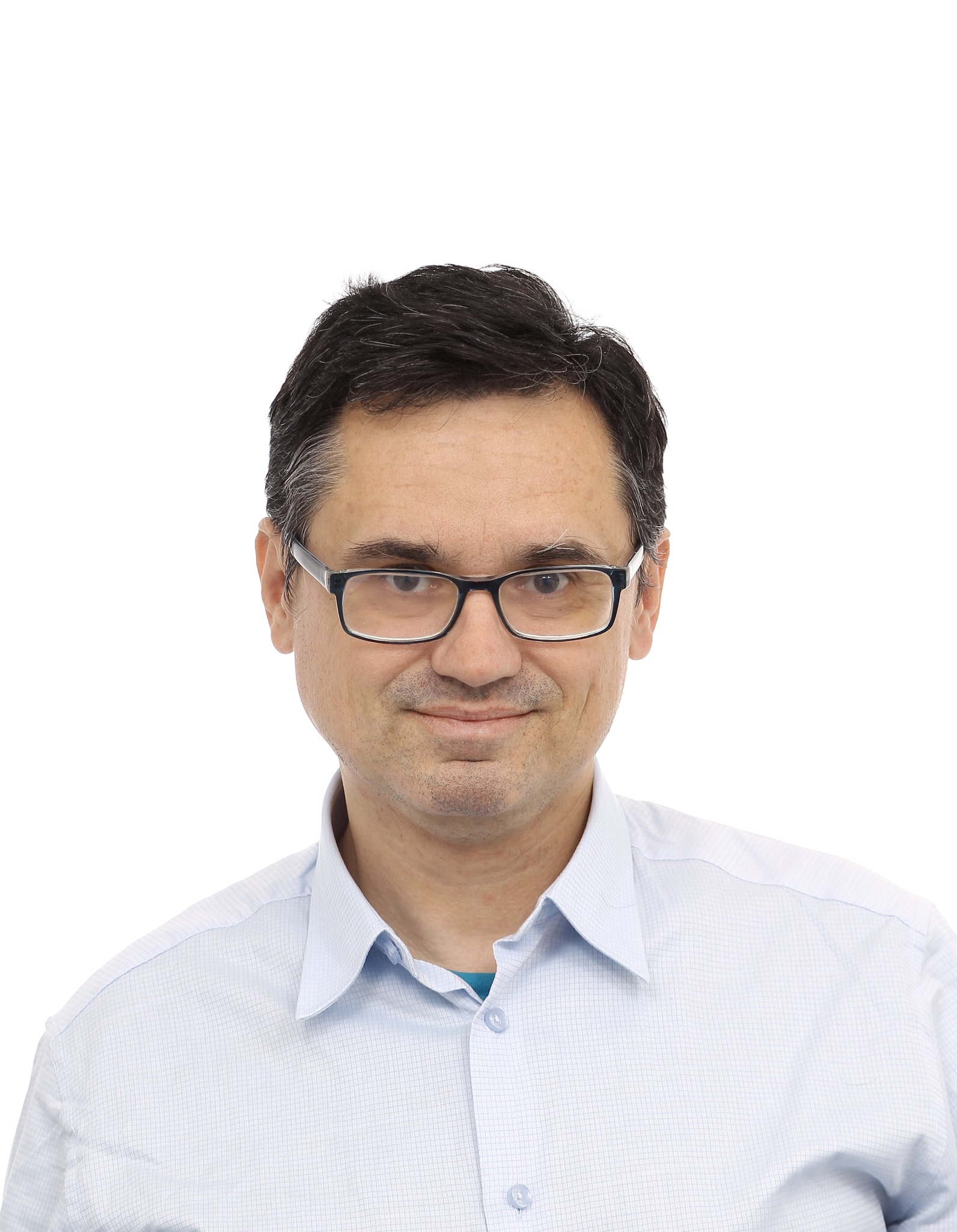 Portret mężczyzny w okularach i jasnej koszuli na białym tle. Uśmiechnięty, z krótkimi, ciemnymi włosami. Wygląda profesjonalnie i budzi zaufanie.