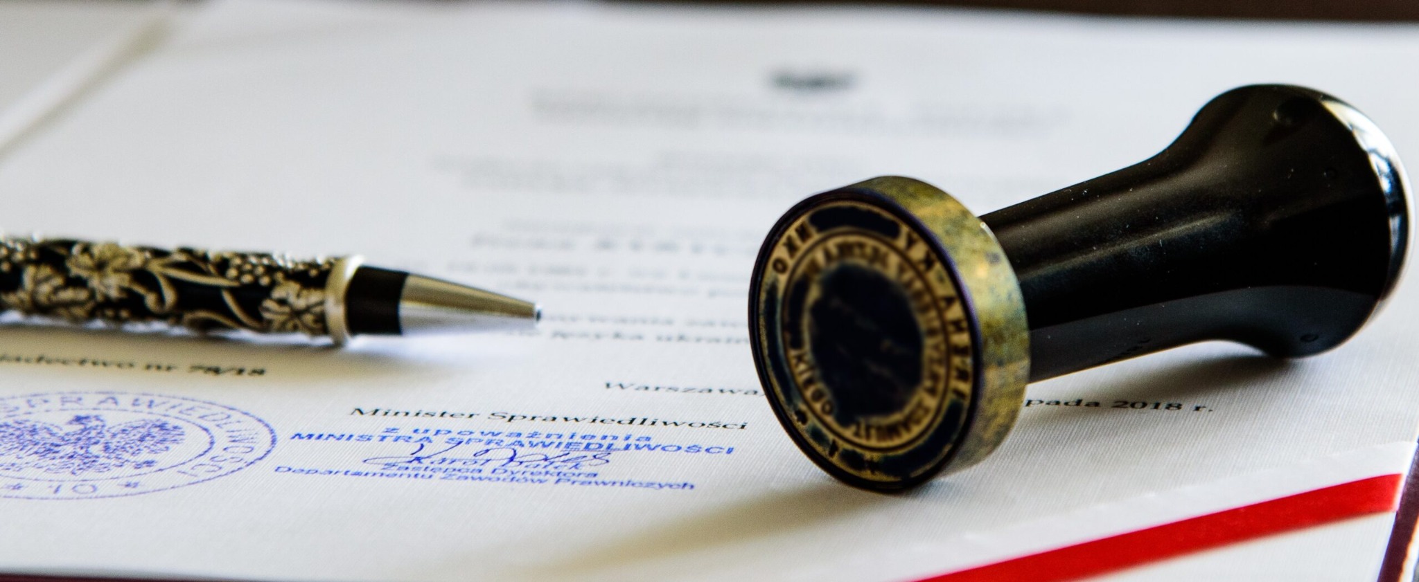 Dokument z pieczęcią Ministra Sprawiedliwości, ozdobne pióro i stempel. Bliski plan detali, ostre światło.