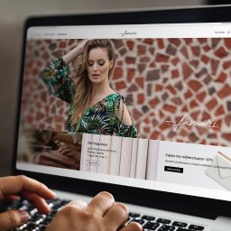 ALFABET MARKI SPÓŁKA Z OGRANICZONĄ ODPOWIEDZIALNOŚCIĄ - Ekran laptopa wyświetlający stronę internetową sklepu odzieżowego 'Famari' z modelką w tropikalnej sukience na tle mozaiki z cegieł, dłonie osoby piszą na klawiaturze.