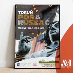 ALFABET MARKI SPÓŁKA Z OGRANICZONĄ ODPOWIEDZIALNOŚCIĄ - Plakat reklamowy z hasłem 'Toruń Pora Ruszać' i zdjęciem pomnika Mikołaja Kopernika, zachęcający do odkrywania Torunia tego lata, w czarnej ramie.