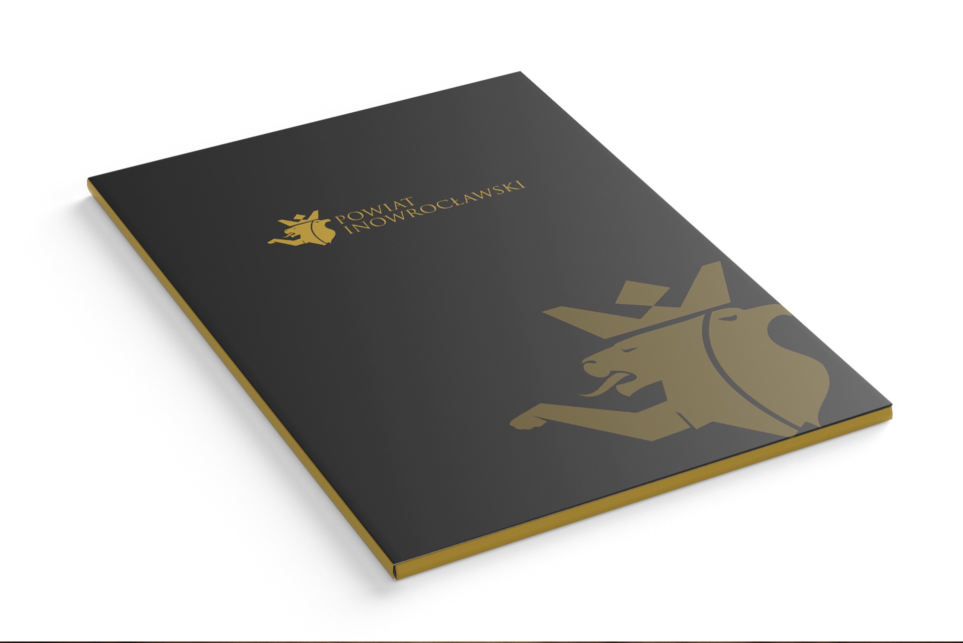 Czarna teczka z logo Powiatu Inowrocławskiego w kolorze złotym, widoczna z perspektywy, leżąca na białym tle.