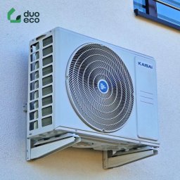 Duoeco Sp. z o.o. - Zewnętrzna jednostka klimatyzacji Kaisai zamontowana na jasnej ścianie budynku, widoczne mocowania i logo Duo Eco w lewym górnym rogu.