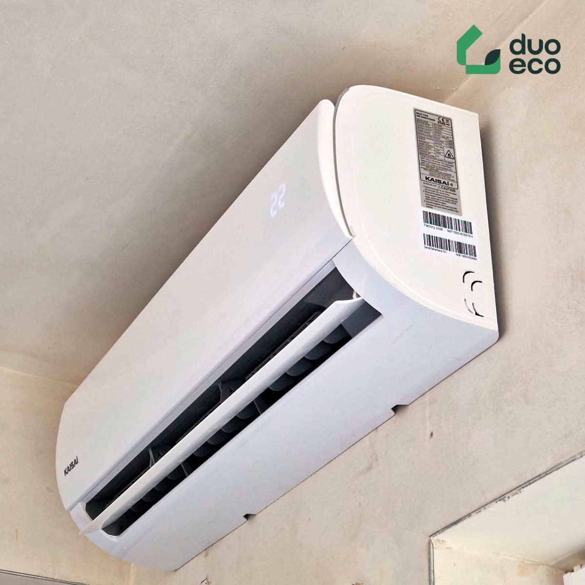 Biały klimatyzator Kaisai zamontowany na ścianie, widoczny wyświetlacz z temperaturą 22 stopnie, logo Duo Eco w prawym górnym rogu.