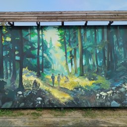 Tigran Vardikyan - Duży mural na drewnianej tablicy pod zadaszeniem, przedstawiający słoneczny las z wysokimi drzewami, ścieżką i trzema postaciami wędrującymi, z grzybami na pierwszym planie.