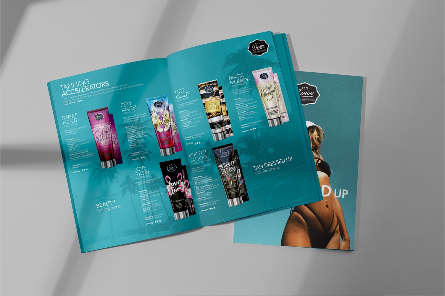 Otwarty katalog reklamowy z kosmetykami do opalania Tan Desire, prezentujący różne produkty z serii i ich składniki, obok leży zamknięty katalog z wizerunkiem opalonej modelki.