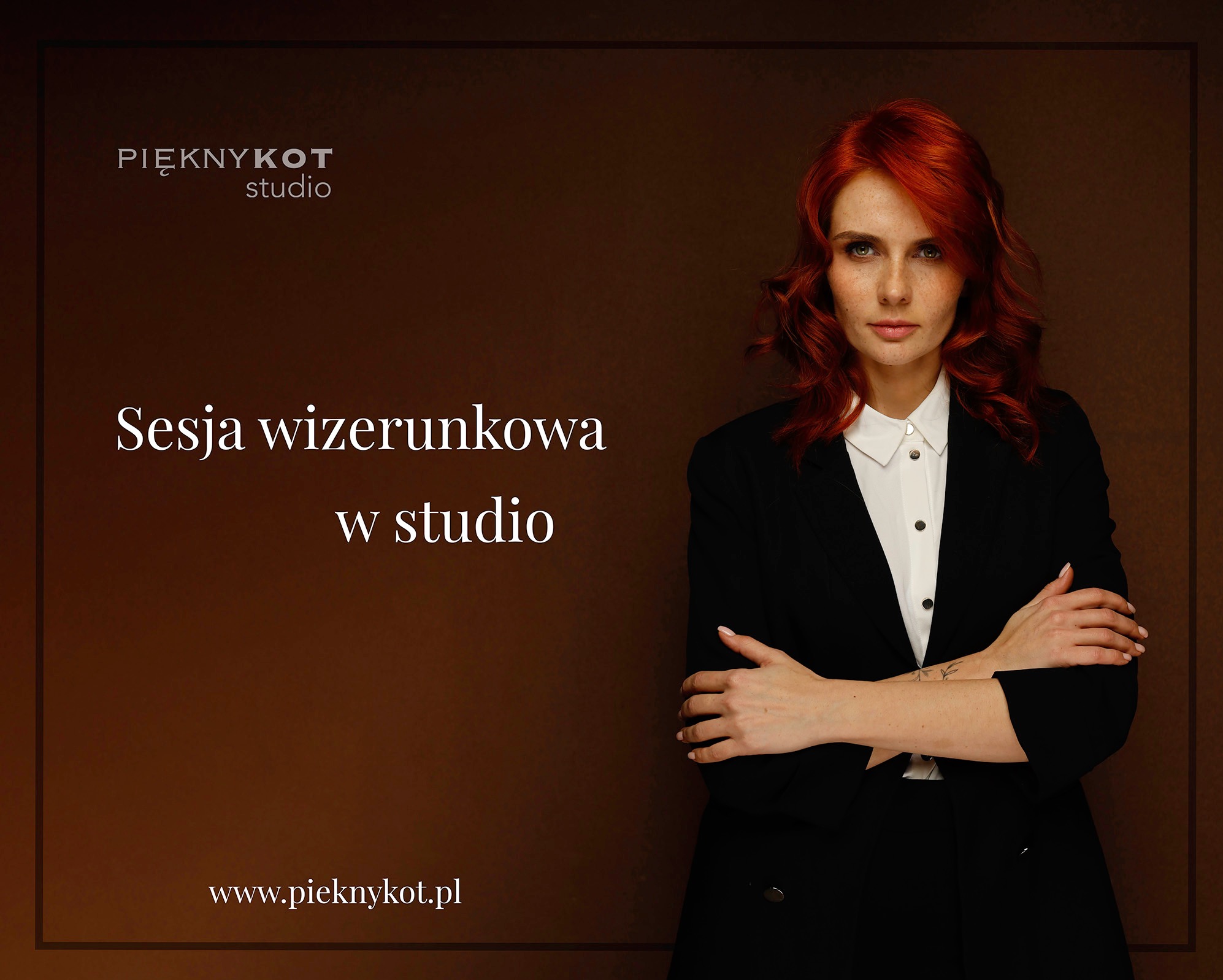 Portret kobiety z rudymi włosami w czarnym garniturze, skrzyżowane ręce, studio z brązowym tłem, logo studia widoczne w lewym górnym rogu.