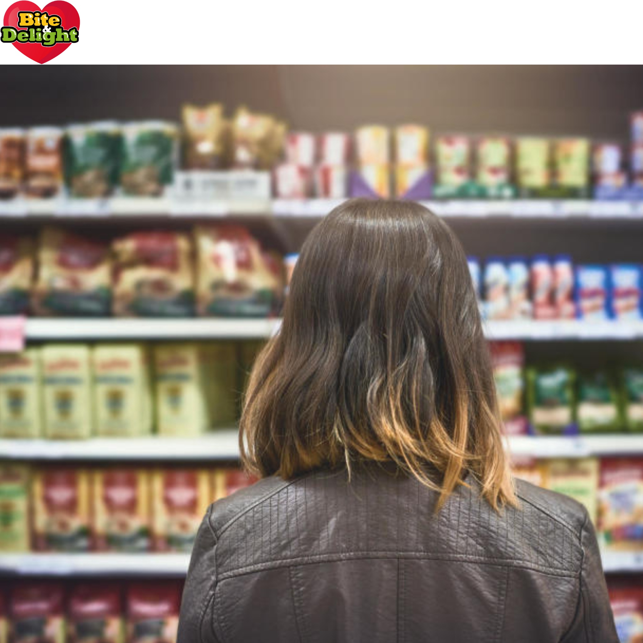 Kobieta w skórzanej kurtce stoi przed półką sklepową wypełnioną różnorodnymi produktami w opakowaniach, logo Bite Delight w lewym górnym rogu.