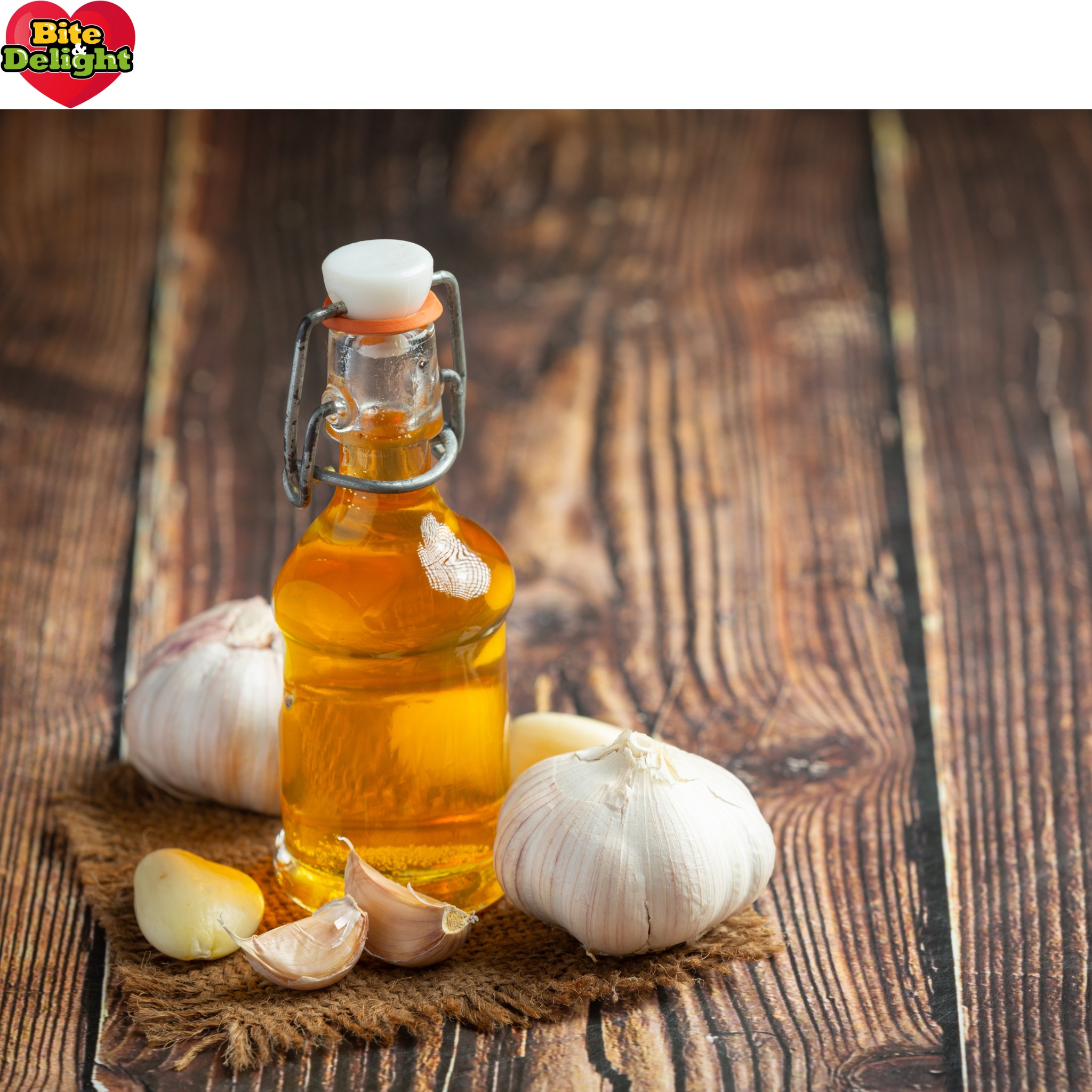 Butelka z olejem czosnkowym na rustykalnym drewnianym stole, otoczona ząbkami czosnku na jutowej ściereczce.