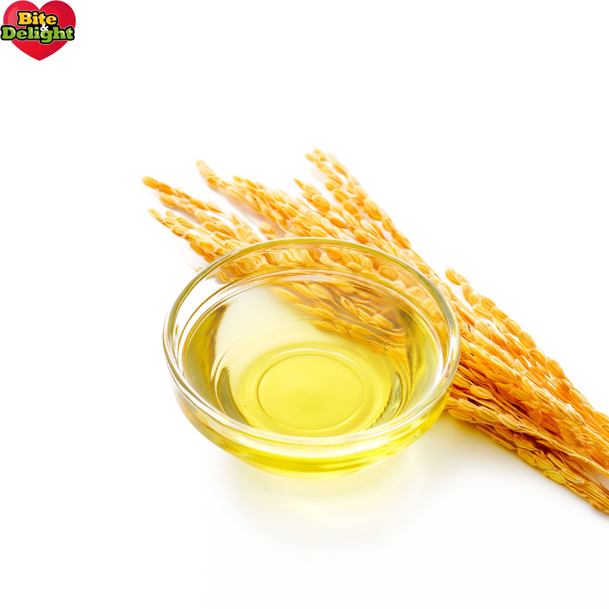 Szklana miseczka z olejem ryżowym obok kłosów ryżu na białym tle.