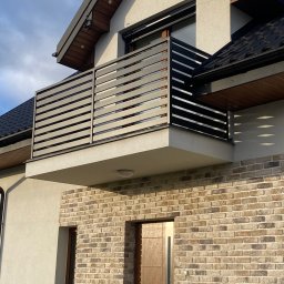 KULESZA WELD Kamil Kulesza - Nowoczesny balkon z poziomą balustradą z metalowych profili na tle elewacji z cegły klinkierowej i jasnego tynku.