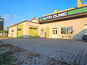 Budynek warsztatu Auto Clinic z zielonymi akcentami i napisem 'Mechanika Samochodowa' na fasadzie, widoczny z zewnątrz, w słoneczny dzień. Kostka brukowa na pierwszym planie.
