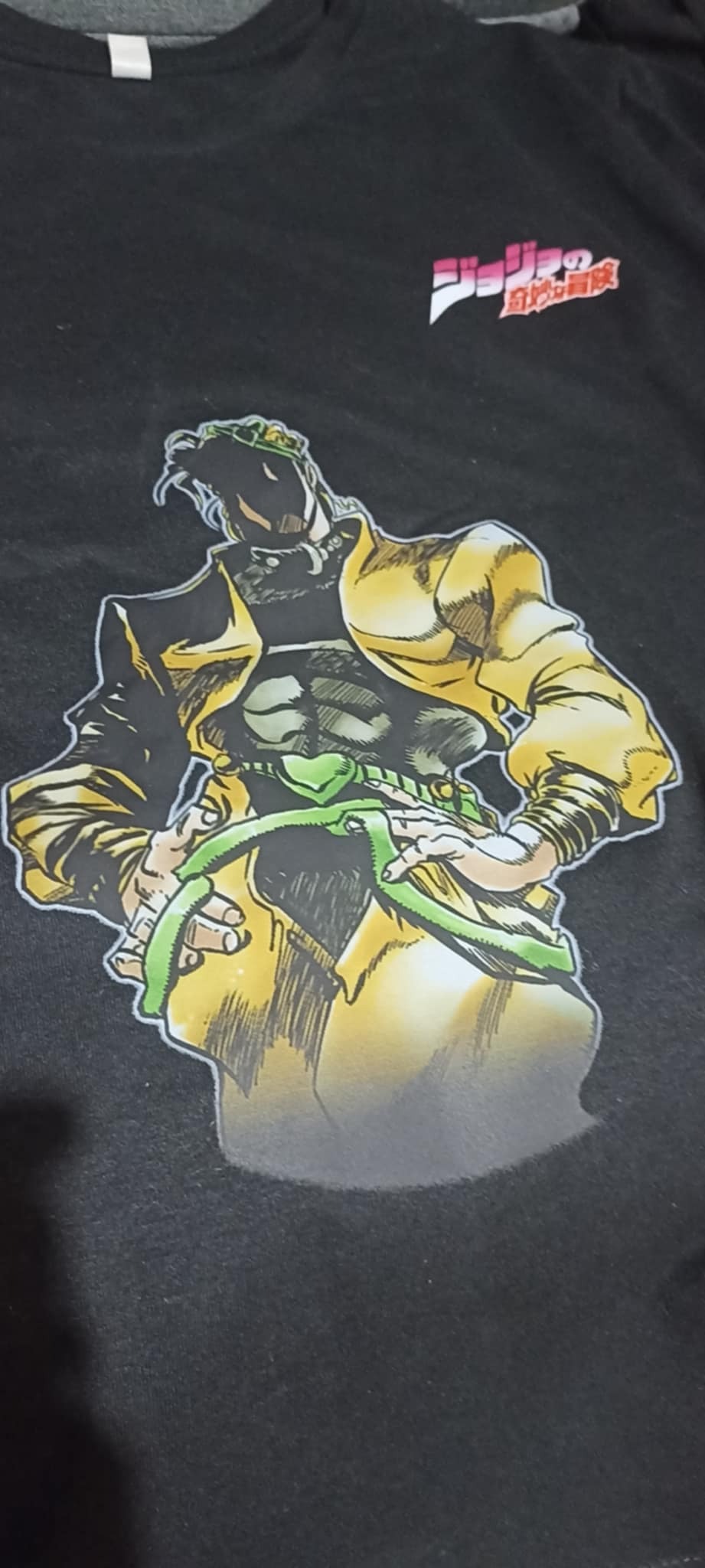 Czarna koszulka z nadrukiem postaci z anime JoJo's Bizarre Adventure, Dio Brando, w żółto-zielonej kolorystyce.