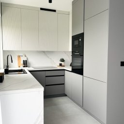 invero studio - Nowoczesna, narożna kuchnia w odcieniach szarości i bieli z marmurowym blatem i minimalistycznym oświetleniem punktowym. Fronty górnych szafek z subtelnym, pionowym frezem.