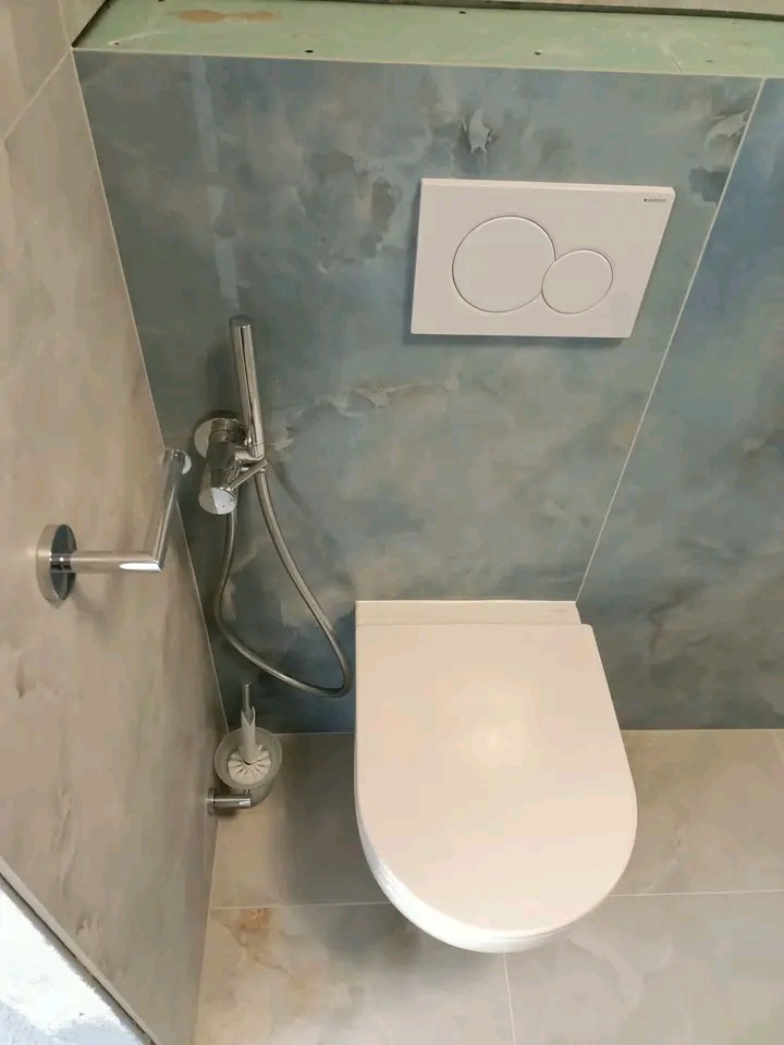 Nowoczesna toaleta wisząca z bidetką i przyciskiem spłukującym Geberit na ścianie w odcieniach błękitu i beżu. Minimalistyczny design, widok z góry.