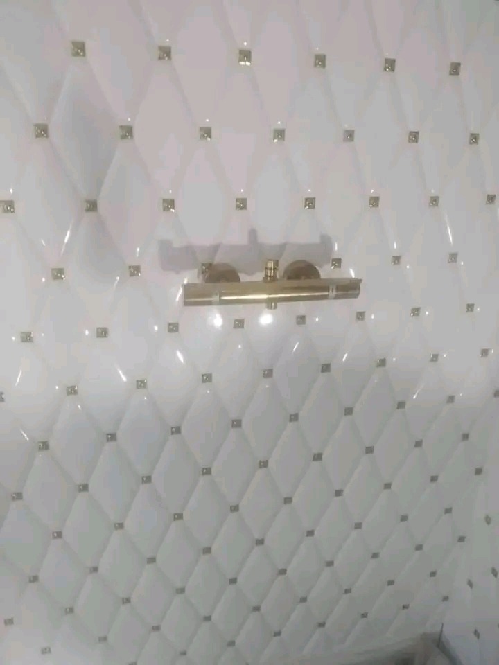 Biała, pikowana ściana w łazience z armaturą w kolorze złota. Eleganckie wykończenie w Malborku. Dekoracyjne płytki imitujące tapicerowane panele.