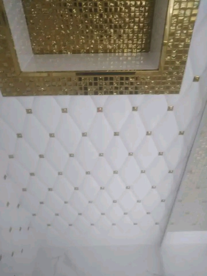 Wykończona łazienka: białe płytki ścienne z wypukłym wzorem rombów i złotymi akcentami, sufit z złotą mozaiką. Luksusowe i eleganckie wykończenie.