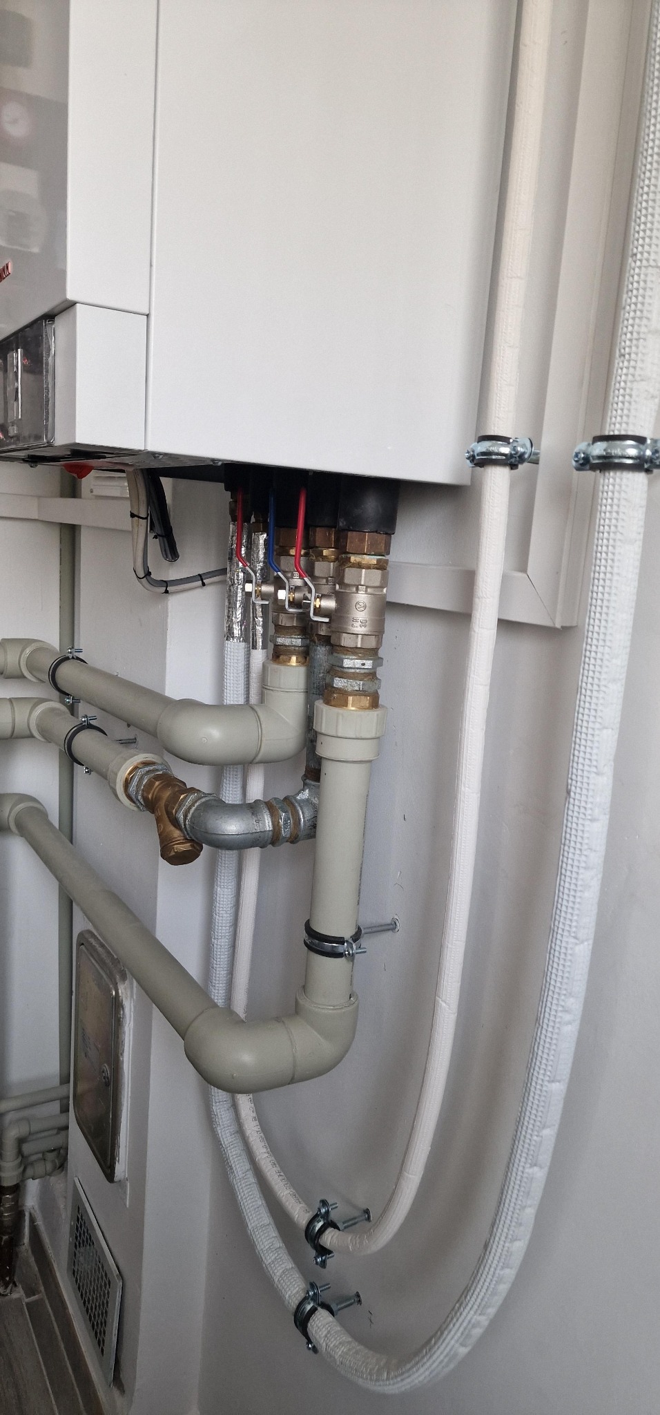 Zamontowany piec gazowy z podłączeniami hydraulicznymi w Pokrzywnie. Widoczne rury z zaworami i izolowane przewody. Estetyczne i funkcjonalne rozwiązanie.