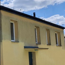 URBAN ALPSERWIS SPÓŁKA Z OGRANICZONĄ ODPOWIEDZIALNOŚCIĄ - Żółta elewacja budynku w trakcie renowacji, widoczne fragmenty świeżo pomalowanej ściany, okna z białymi ramami, na dachu antena.