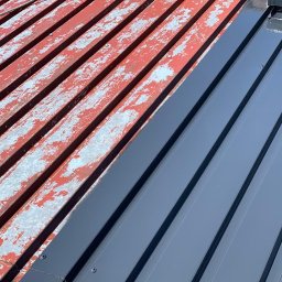 URBAN ALPSERWIS SPÓŁKA Z OGRANICZONĄ ODPOWIEDZIALNOŚCIĄ - Częściowo pomalowany blaszany dach: stara, łuszcząca się czerwona farba kontrastuje z nową, gładką, szarą powłoką. Widoczne mocowania.