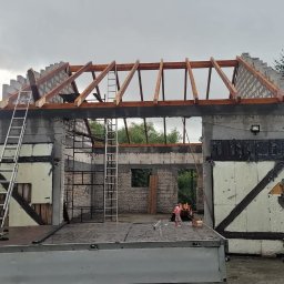 Sebastian Skrentny - Budynek w trakcie budowy dachu, widoczne krokwie i pustaki, drabiny przystawione do ściany, na pierwszym planie platforma samochodu dostawczego.