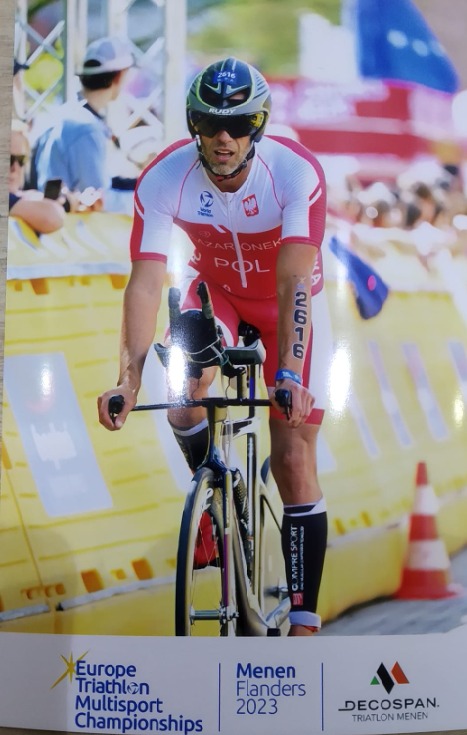 Triatlonista w stroju reprezentacji Polski, z numerem 2616 na ramieniu, na rowerze podczas zawodów Europe Triathlon Multisport Championships Menen Flanders 2023.