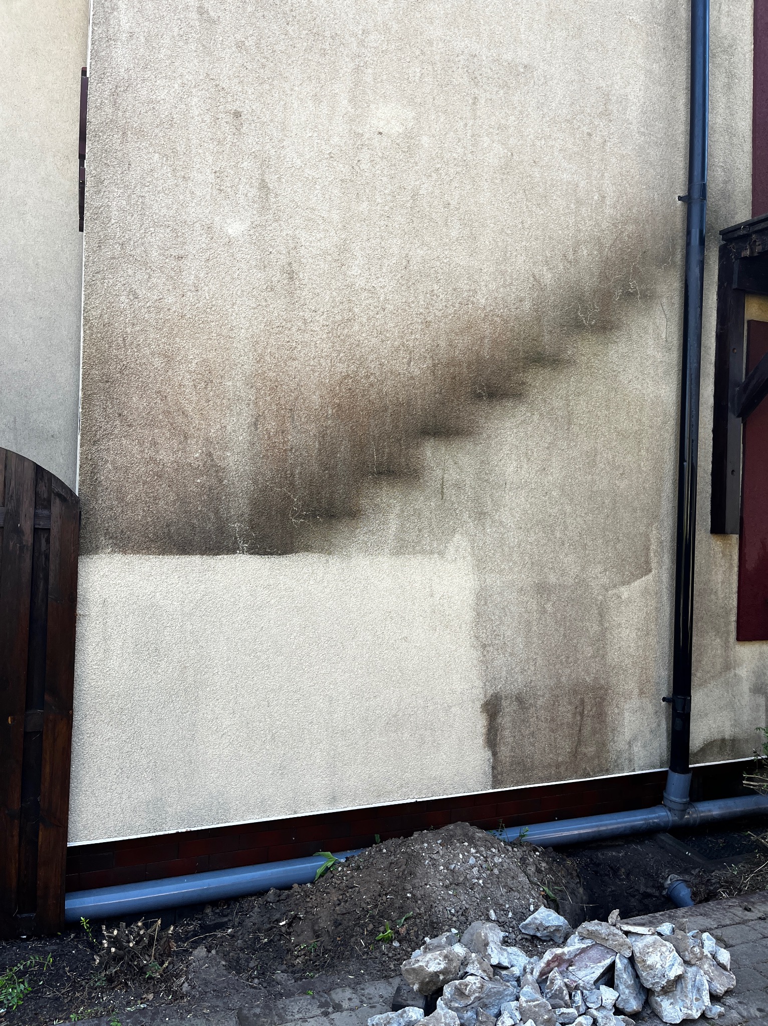 Elewacja budynku przed i po czyszczeniu we Władysławowie. Widoczny kontrast między umytą a zabrudzoną powierzchnią, zarys schodów na ścianie.