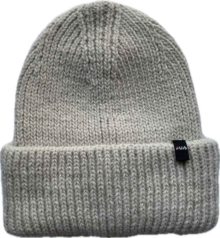 Beżowa, dziergana czapka z podwiniętym brzegiem i małą, czarną metką z logo po prawej stronie.