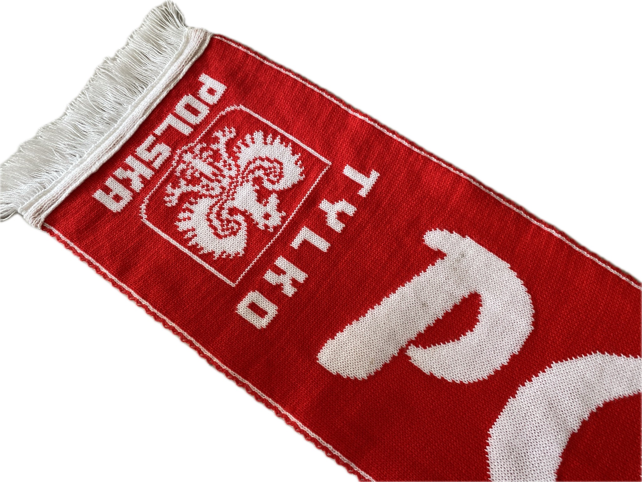 Czerwony, dziergany szalik kibica z białym godłem Polski, napisem 'Polska' i 'Tylko', wykończony białymi frędzlami.