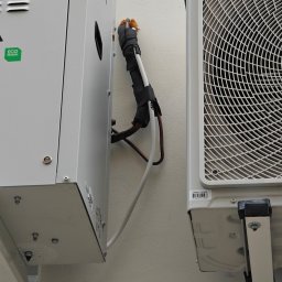 Arbilem Daria Piechota - Dwa moduły klimatyzacyjne zamontowane na ścianie, z widocznymi rurami i izolacją. Jeden z modułów ma naklejkę 'ECO DESIGN'.